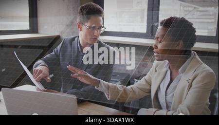 Er spricht über Kollegen in Blazern, Mann mit Brille, der auf Papier im Büro zeigt, Laptop sichtbar Stockfoto
