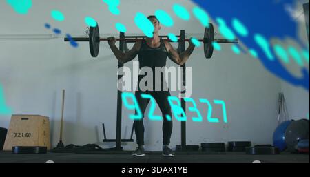 Ein muskulöser Mann in einem schwarzen Tank, der eine geladene Langhantel auf einem Hocker im Fitnessstudio hält, mit HUD Stockfoto