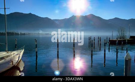 Sonnenaufgangslinse Flare over Foggy Lake and Mooring Posts Stockfoto