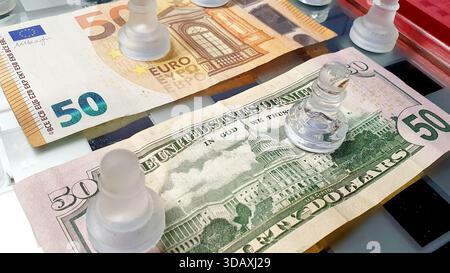 Zwei 50 US-Dollar- und 50-Euro-Scheine stehen einander auf einem Schachbrett gegenüber, in einem Spiel der Vorherrschaft und des Handelskollegienkrieges. Stockfoto