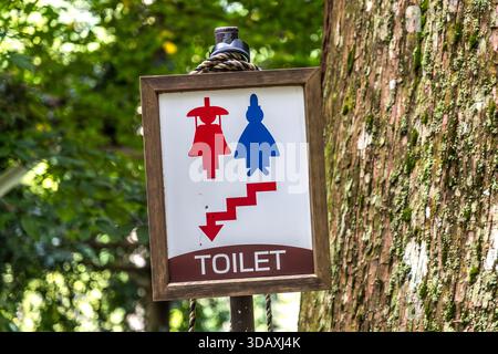 Ein Wegweiser in der Nähe der Nachi-Fälle markiert die Toiletten mit Heian-Stil-Figuren für Männer und Frauen. Nachikatsuura, Präfektur Wakayama, Japan. Stockfoto
