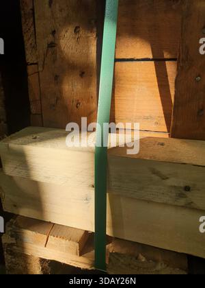 Sonnenlicht fällt auf die Holzstangen, die Gitter sind mit Plastikband bedeckt, Abstraktion. Hohe Qualität Stockfoto