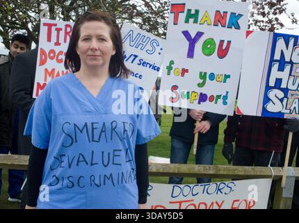Am 26. April 2016 bildeten Ärzte des Queen Elizabeth Hospital in King's Lynn, Norfolk, am ersten Tag ihres beispiellosen All-Out-Streiks Streikposten – der erste in der Geschichte des NHS, der die Notversorgung entzog. Sie protestierten gegen den von Gesundheitsminister Jeremy Hunt auferlegten neuen Vertrag, der Wochenendprämien reduzierte, die „normalen“ Stunden verlängerte und als unterbewertete Ärzte angesehen wurde, während sie Patienten bei der Verfolgung eines siebentägigen NHS gefährdeten. Auf Schildern werden Botschaften wie „Hunt Must Go“ und „Safe Staffing rettet Leben“ angezeigt. Trotz Kontroversen fand die Aktion breite Unterstützung der Öffentlichkeit. Stockfoto