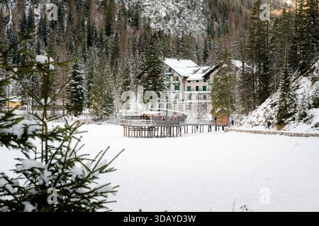 Hotel Lago di Prags im Winterschnee, mit dem gefrorenen See im Vordergrund und den dramatischen Berggipfeln der Dolomiten im Hintergrund, c Stockfoto
