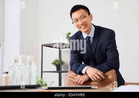 Ein chinesischer Geschäftsmann lehnt sich im Büro auf einen Stuhl Stockfoto
