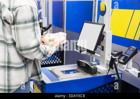 Ein Kunde hält Pilze an einer Selbstkasse in einem Supermarkt. Hochwertige Fotos Stockfoto