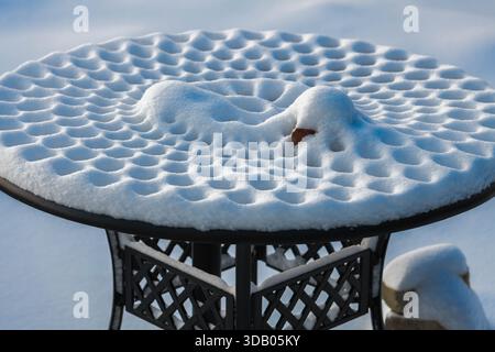 Auf einem Picknicktisch aus Metall bilden sich zarte Schneedesigns, die die Kunstfertigkeit der Natur in einer ruhigen Winterszene in Ludington, Michigan, USA, zeigen Stockfoto