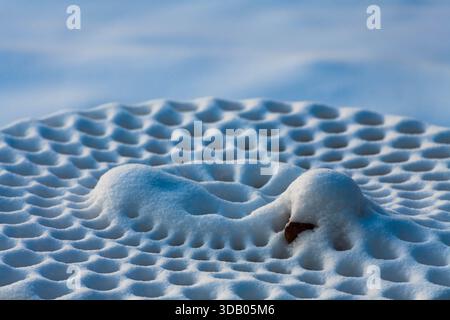 Ein Picknicktisch aus Metall mit frischem Schnee zeigt atemberaubende Muster, die die Schönheit der Natur mit der Ruhe des Winters in Ludington, Michigan, verbinden Stockfoto