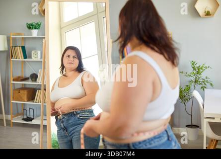 Frau In Übergröße Misst Zu Hause Die Taille Vor Dem Spiegel Stockfoto