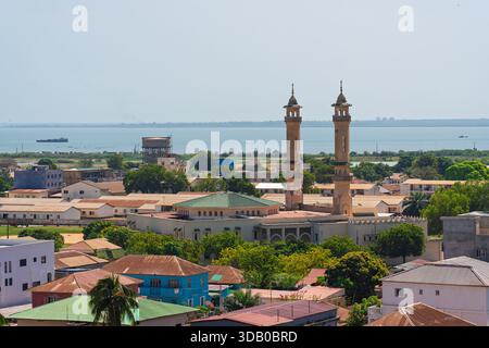 Banjul, Gambia. Erhöhter Blick auf die Stadt mit einer großen Moschee, Wohndächern und der entfernten Flussmündung Stockfoto