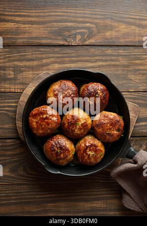 Hackschnitzel aus Schweinefleisch und Rindfleisch in einer gusseisernen Pfanne auf hölzernem Hintergrund mit freiem Platz. Draufsicht, flach Stockfoto