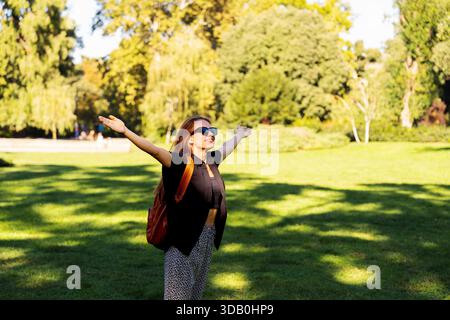 Glückliche Frau, die die Natur mit offenen Armen im grünen Park umgibt Stockfoto