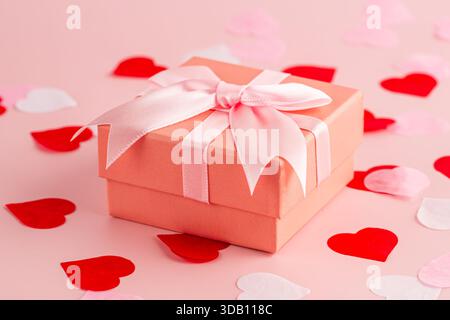 Eine Valentinstag-Geschenkbox, kleine rosa, rote und weiße Herzen auf rosa Hintergrund. Stockfoto