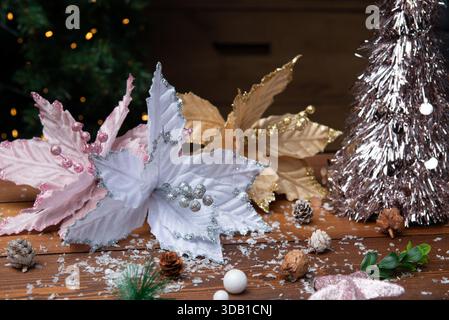 Rustikale Weihnachtsszene: Elegante weiße und goldene Poinsettias mit rosafarbenen Seestern auf einem Holztisch Stockfoto