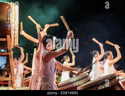 Synchronisiertes Percussion-Ensemble aus U-Theatre mit großen Trommeln und hölzernen Bachi während eines lebendigen Kulturfestivals. Stockfoto