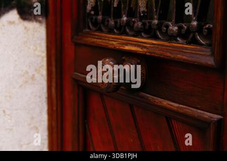 Vintage-Holztür mit kunstvollem Knopf und Eisengitter. Stockfoto