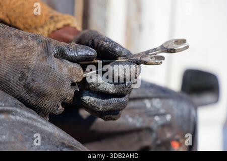 afrikanischer Arbeiter Nahaufnahme der Hände, Schlüssel halten, Handschuhe tragen, Handarbeit tragen, eine Warnweste und ein langärmliges Hemd tragen, Sicherheit Stockfoto