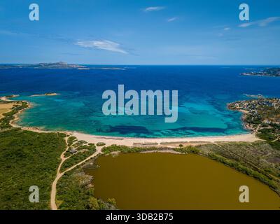 Atemberaubende Luftaufnahme einer türkisfarbenen Küstenbucht mit Sandstrand, üppigem Grün und einer braunen Lagune, Sardinien, Italien Stockfoto