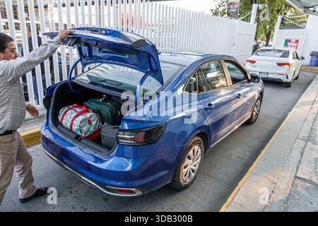 Puebla Mexico, CAPU Central de Autobus de Puebla Bushaltestelle, außen, Gepäck in den Kofferraum laden, blaue Limousine parkt, Mann Erwachsene männliche Hebezeuge Stockfoto