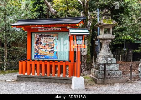 Eine Informationstafel mit einer illustrierten Karte von Kumano Hayatama Taisha steht neben einer Steinlaterne und einer Holzlaterne in Shingū, Präfektur Wakayama, Japan. Die Tafel ist mit "熊野速玉大社参拝略図" beschriftet (ungefähr: Übersichtskarte für Schreinbesucher); der Schrein ist einer der drei Großschreine von Kumano (Kumano Sanzan) und seit 2004 UNESCO-Weltkulturerbe. Stockfoto