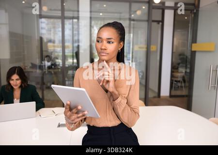 Nachdenkliche junge schwarze Geschäftsfrau, die über zukünftige Projekte denkt Stockfoto