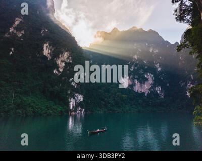 Das neblige Morgenlicht beleuchtet das ruhige Wasser des Cheow Lan Lake, umgeben von atemberaubenden Kalksteinklippen im Khao Sok Nationalpark Thailand Stockfoto