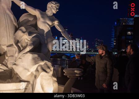London, Großbritannien. Dezember 2025. Ein Gast füllt sein Glas mit Peroni aus dem Brunnen am South Bank in London. Premium-Bier, Peroni Nastro Azzurro installierte einen Brunnen namens La Fontana di Azzurro auf Italienisch. Er basiert auf dem Trevi-Brunnen in Rom und befindet sich am Aussichtspunkt im South Bank, London. Die Besucher können kostenlos ein Bier aus dem Brunnen trinken. Es dauert vom 10. Bis 14. Dezember 2025, um der Nation Feiertagsstimmung zu bringen. (Foto: Krisztian Elek/SOPA Images/SIPA USA) Credit: SIPA USA/Alamy Live News Stockfoto