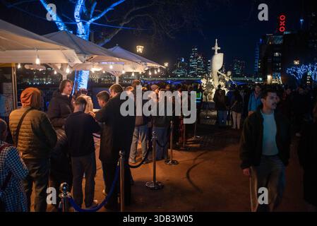 London, Großbritannien. Dezember 2025. Gäste werden beim kostenlosen Peroni-Bier im South Bank in London anstehen sehen. Premium-Bier, Peroni Nastro Azzurro installierte einen Brunnen namens La Fontana di Azzurro auf Italienisch. Er basiert auf dem Trevi-Brunnen in Rom und befindet sich am Aussichtspunkt im South Bank, London. Die Besucher können kostenlos ein Bier aus dem Brunnen trinken. Es dauert vom 10. Bis 14. Dezember 2025, um der Nation Feiertagsstimmung zu bringen. (Foto: Krisztian Elek/SOPA Images/SIPA USA) Credit: SIPA USA/Alamy Live News Stockfoto