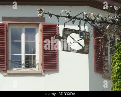 STRASSBURG, FRANKREICH - 27. MAI 2025 - altes hölzernes Restaurantschild mit Messer und Gabel, mit einem Fenster und roten Fensterläden auf dem Hintergrund in Strasb Stockfoto