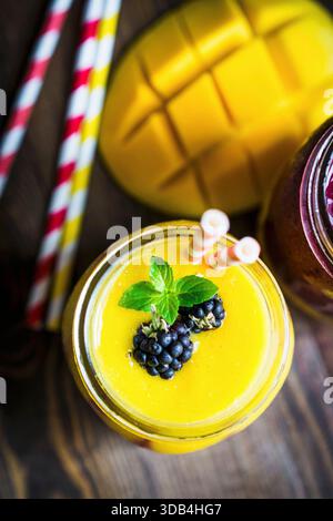 Mehrlagiger Mango- und Beeren-Smoothie garniert mit Brombeeren Stockfoto