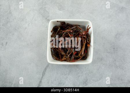Ein Blick von oben nach unten auf eine kleine quadratische Schüssel mit Löwenzahn Kimchi. Stockfoto