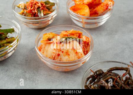 Blick auf eine kleine Glasschale mit Kimchi, umgeben von einer Vielzahl von Kimchi. Stockfoto