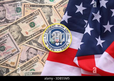 KIEW, UKRAINE - 13. DEZEMBER 2025 Siegel des Präsidenten der Vereinigten Staaten Aufkleber auf großen Mengen von US-Dollar-Geldscheine Banknoten und die Flagge der Vereinigten Staaten in Nahaufnahme Stockfoto
