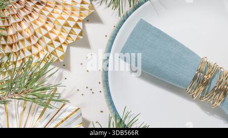 Weihnachtsfeiertagstisch Mit Serviette Aus Blauem Leinen, Weißer Teller Und Goldenen Festakzenten. Perfekt für Einladungen zu Weihnachten und Neujahr zum Abendessen, Stockfoto