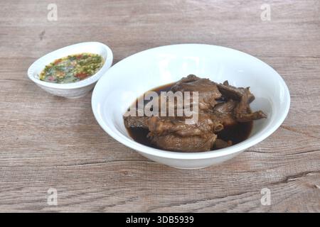 Hacken Sie gekochten Entenflügel-Eintopf in brauner Sojasuppe in einer Schüssel und tauchen Sie würzige Chili-Sauce Stockfoto