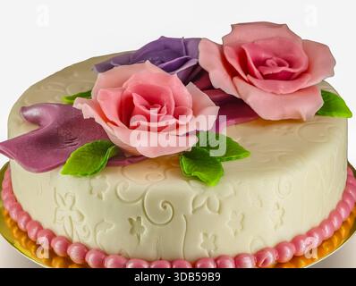 Eleganter weißer Fondant-Kuchen mit rosafarbenen und lila Zuckerrosenblüten für die Geburtstagsfeier Stockfoto