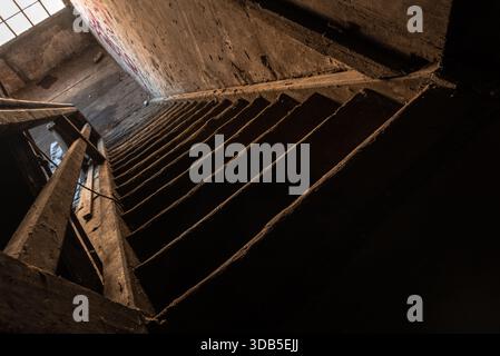 Verlassene Holztreppe im verfallenden Innern mit Moody Light und dramatischen Schatten Stockfoto