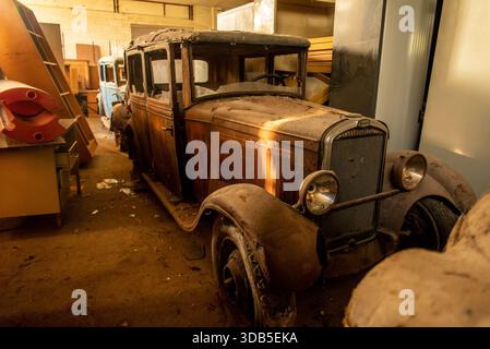 Staubbedeckte antike Limousine in verlassener französischer Garage - Rusty Barn-Find mit Patina und Moody Light Stockfoto