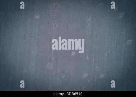 Von oben nach unten auf eine dunkelblau-graue Ackerfläche. Die minimalistische Komposition zeichnet sich durch schwache vertikale Bodenlinien und dezente Aufprallmarkierungen aus, die eine stimmungsvolle abstrakte Hintergrundstruktur erzeugen. Stockfoto