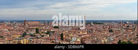 Panoramablick auf die rot gekachelten Dächer und mittelalterlichen Türme von Bologna, einschließlich Asinelli, Garisenda und San Petronio Basilika unter wolkenbewölktem Sommerhimmel. Stockfoto