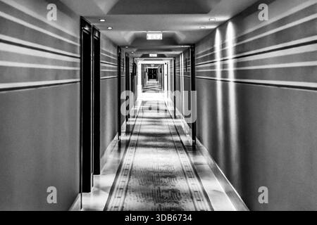 Lange beleuchtete Hotelflur bei Nacht in einem Luxusresort in Chalkidiki, Griechenland, in Schwarz-weiß fotografiert. Stockfoto