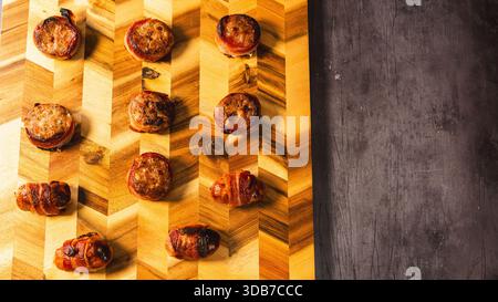 Festliches Brett mit Schweinen in Decken und mit Speck umwickelten Schweinefleisch-Snacks, wunderschön eingerichtet. Perfekt für Weihnachts- und Silvesterpartys, bereit zum Teilen Stockfoto