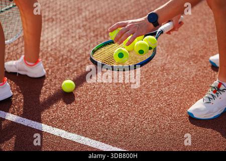 Nahaufnahme von Tennisspielern, die während des Trainings mit Schlägern auf dem Außenplatz Bälle abheben. Stockfoto