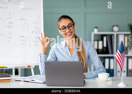 Freundliche weibliche Lehrerin gibt Online-Englischunterricht mit Laptop und lächelt Webcam an Stockfoto