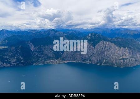 Blick aus der Vogelperspektive auf Limone sul Garda am westlichen Gardasee mit terrassenförmig angelegten Hängen, dichtem Dorf und umliegenden Alpenvorbergen. Stockfoto