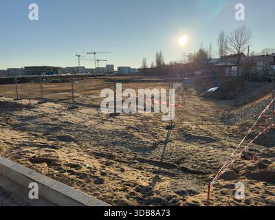 Leeres Stadtgrundstück verwandelt sich in neue Wohnungen mit sichtbaren Baukränen Stockfoto