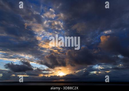 Dramatischer tropischer Sonnenuntergang mit hoch aufragenden Sturmwolken und goldenem Licht über dem Karibischen Meer vor der Küste von Belize. Stockfoto
