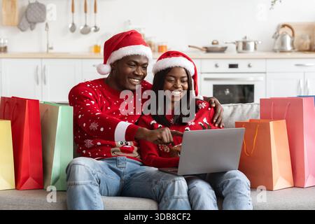 Fröhliches Schwarzes Paar Genießt Während Der Weihnachtszeit Gemeinsam Online-Shopping Stockfoto