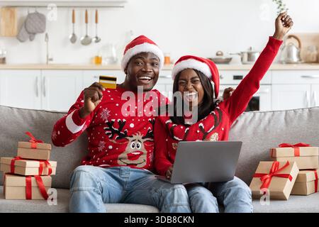Emotionale Familie genießt Online-Weihnachtseinkäufe im gemütlichen Wohnzimmer Stockfoto