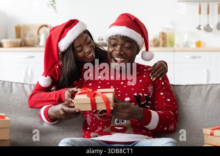 Das Liebespaar feiert Weihnachten zu Hause und tauscht Geschenke aus und teilt freudige Momente Stockfoto